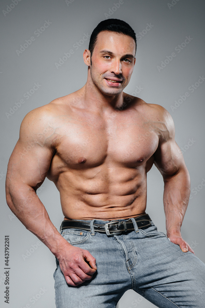 Fototapeta premium A young athlete in jeans poses sitting in the studio. Sport.