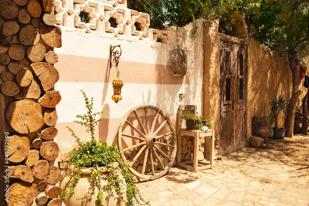 Ethnic style patio with oriental touches, large wooden wheel and potted plants. Afternoon siesta in the sun-drenched courtyard. Authentic ethnic courtyard concept