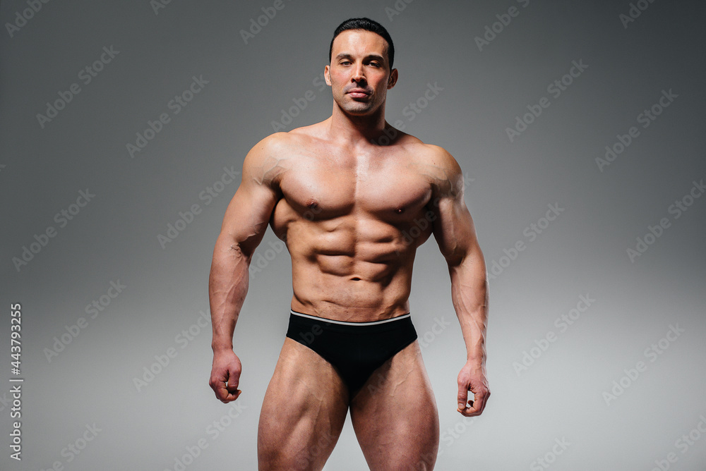 A young athlete bodybuilder poses in the studio topless, showing off his abs and muscles. Sport. A young athlete bodybuilder poses in the studio topless, showing off his abs and muscles. Sport.