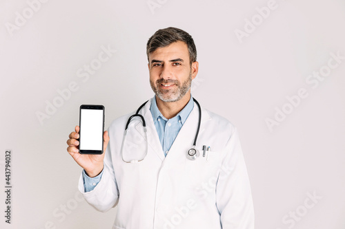 Male doctor holding smartphone on white background
