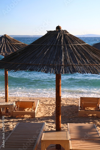 Bamboo parasol and wooden deck chair on a beautiful beach in Croatia.