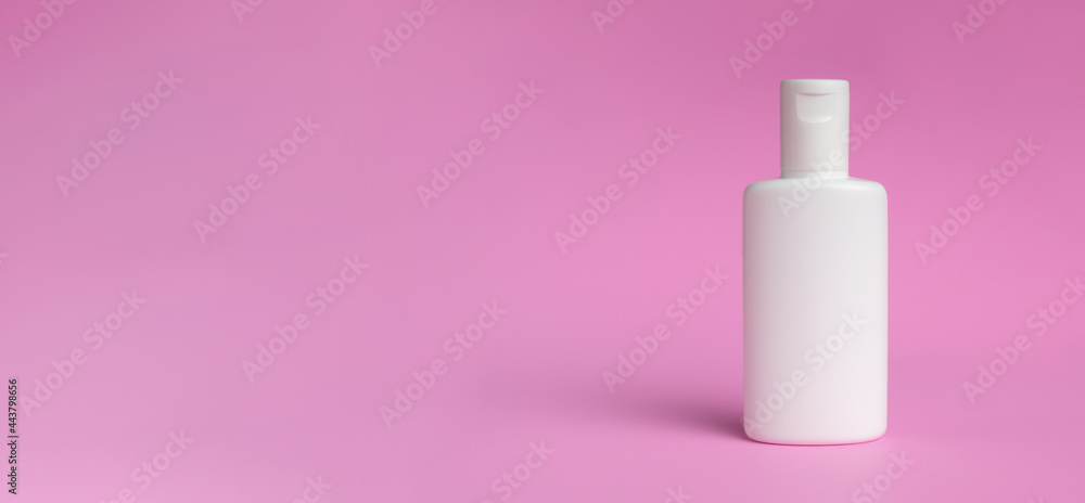 White bottle of lotion or cream isolated on pink background. Shadows blur on the floor White bottle of lotion or cream isolated on pink background. Shadows blur on the floor