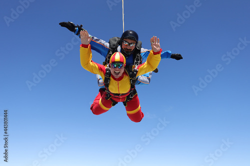 Skydiving. Tandem jump. A happy passenger and her instructor are flying in the sky.