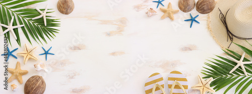 nautical concept with palm leaf, beach hat and starfish over white wooden background