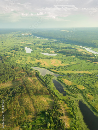 Beautiful summer landscape with a drone on the river, flood meadows, fields, forests. Vertical photo