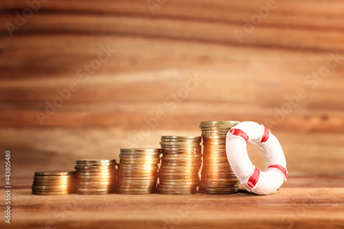 concept image of stacked coins and life bouy over wooden background. banking, funds and assistance idea