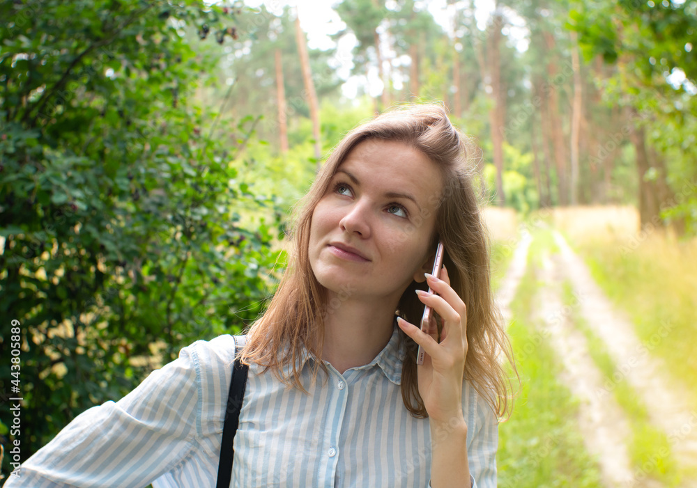 Beautiful girl with fair hair is talking on phone in forest. Young woman lost on the nature. No signal phone connection. Beautiful girl with fair hair is talking on phone in forest. Young woman lost on the nature. No signal phone connection.