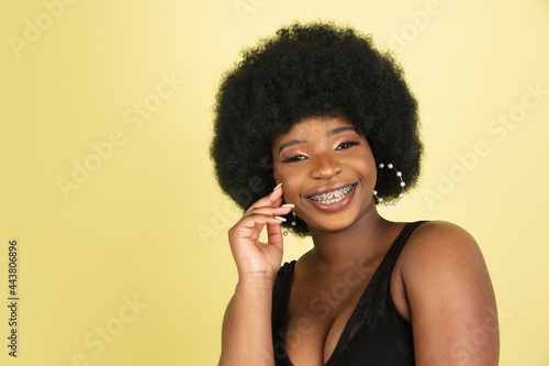 Close-up portrait of happy African young woman isolated over light yellow studio background. Concept of human emotions, facial expression, youth, sales, ad.
