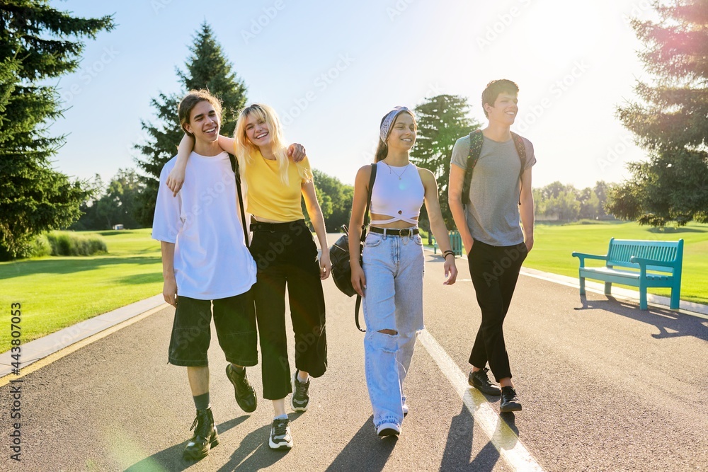 Outdoor, four teenagers walking together on road - obrazy, fototapety, plakaty 