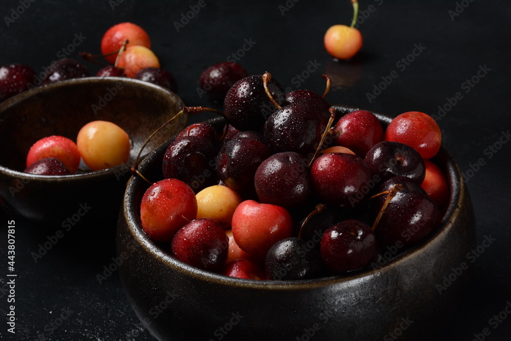 Yellow and red sweet cherries. Fresh ripe sour cherries. Fresh sweet cherries bowl in water drops on stone background Yellow and red sweet cherries. Fresh ripe sour cherries. Fresh sweet cherries bowl in water drops on stone background