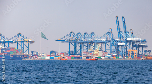 Gantry cranes unload container ships on a sunny summer day