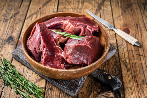 Sliced Beef or veal raw heart in a wooden plate with herbs. wooden background. Top View