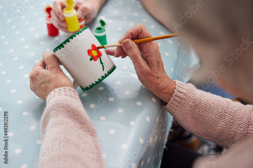 Close Up Of Senior Woman Painting Cup With Art Therapist photo