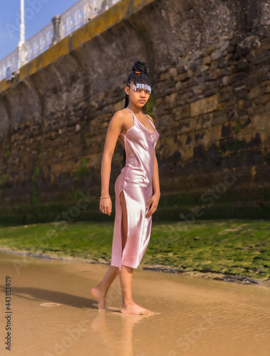 Dominican ethnic girl with braids with a beautiful pink dress. Fashion enjoying the summer walking on the beach