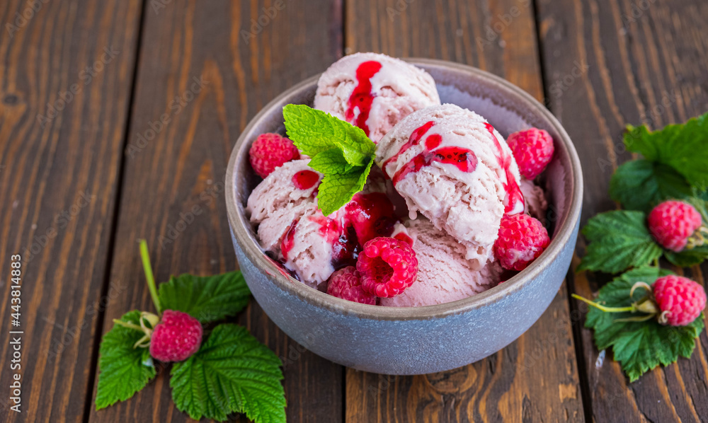 Balls of raspberry ice cream with fresh raspberries in a ceramic bowl on a brown wooden background. Ice cream recipes. Balls of raspberry ice cream with fresh raspberries in a ceramic bowl on a brown wooden background. Ice cream recipes.