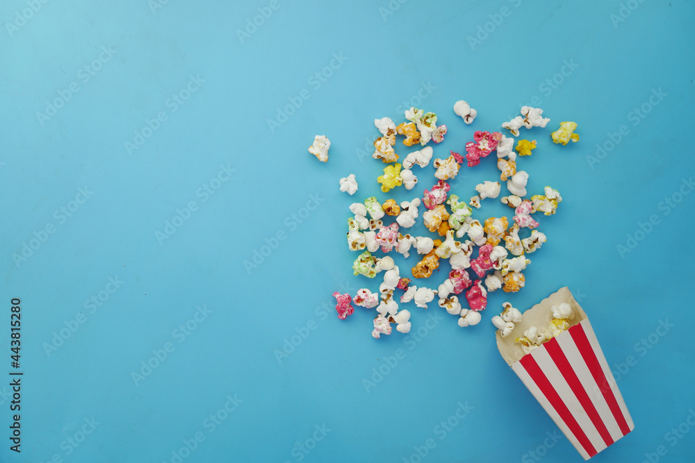  popcorn spilling from a paper container on wooden background 