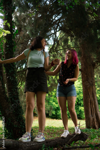 Fototapeta Naklejka Na Ścianę i Meble -  Two young women are smiling while walking through the park.