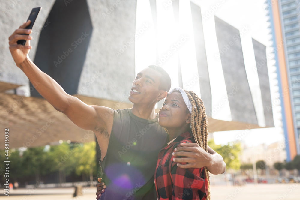 Happy smilng couple taking selfie with phone outdoors. Boyfriend and girlfriend having fun outdoors.