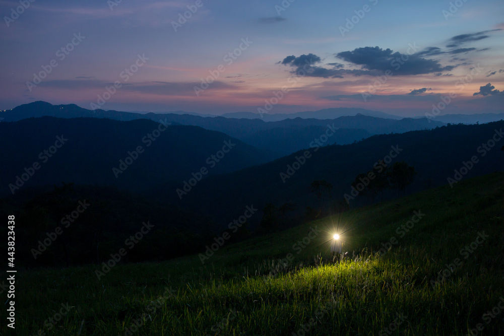night mountain landscape green meadow purple sky after sunset flashlight tourist Dark before destination, background image, and space for the top left text.