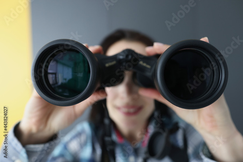 Young woman looking through black professional binoculars closeup