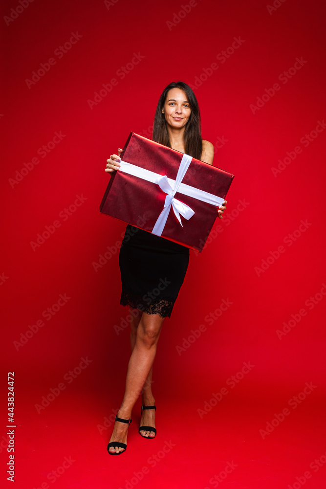 Smiling model in black dress and heels with present. Smiling model in black dress and heels with present.