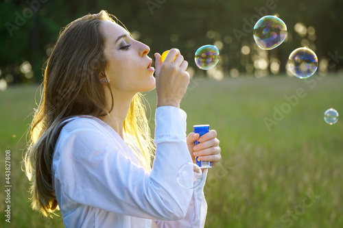 Beautiful woman blowing bubbles in a field on a beautiful summer day