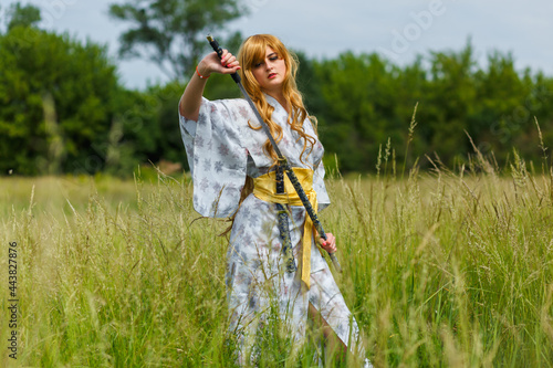 Young asian woman in traditional kimono trains fighting techniques with katana sword