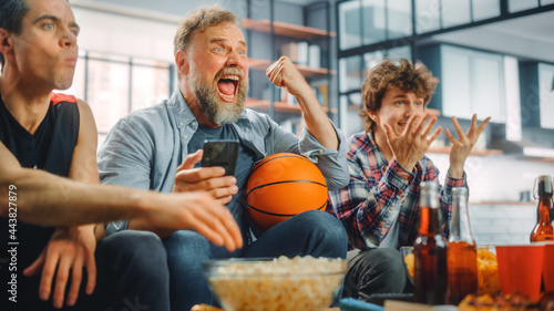 Canvas Print At Home Three Fans Sitting on Couch Watch Basketball Game on TV, Use Smartphone App for Checking Score, Bet, Statistics, Celebrate when Team Wins Championship
