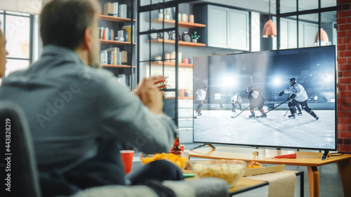 Photography At Home Ice Hockey Fans Sitting on a Couch Watch Game on TV, Cheer when Favourtite Sports Team to Win the Championship