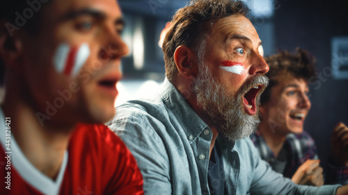 Fotografie At Home Three Joyfuls Sports Fans with Painted Faces Sitting on a Couch Watch Game on TV, Celebrate Victory when Sports Team Wins Championship