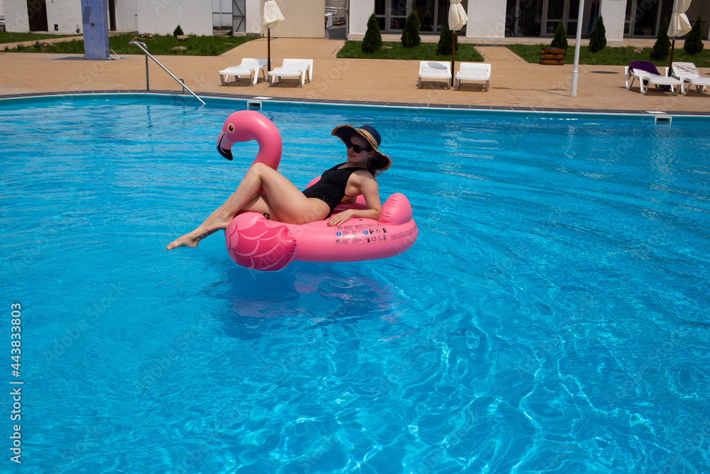 Happy woman on flamingo pool float in pool. Summer holidays
