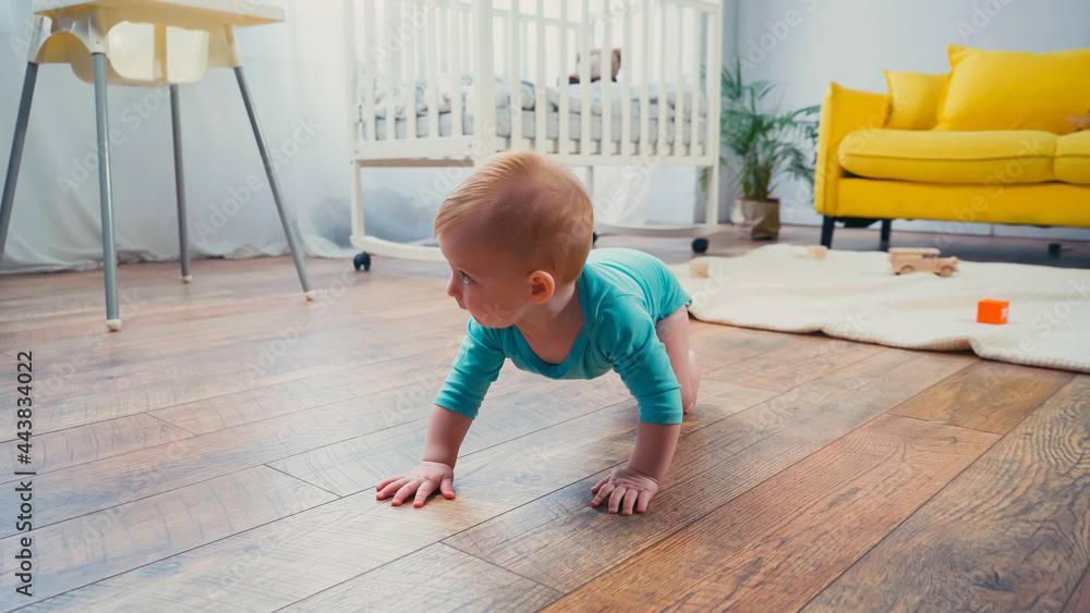 infant boy crawling on floor near feeding chair in living room infant boy crawling on floor near feeding chair in living room