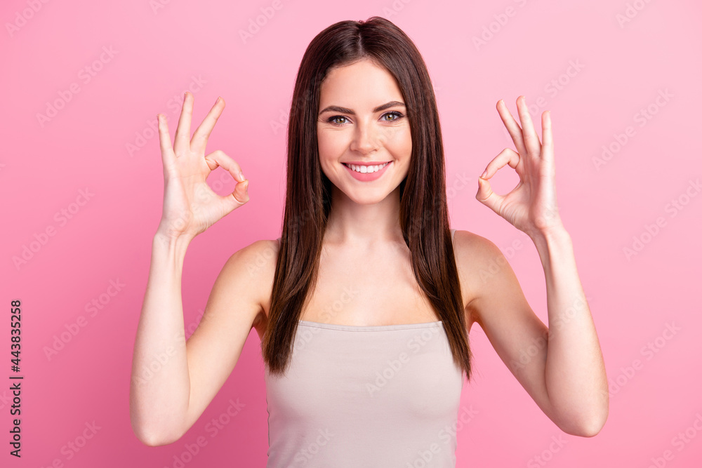 Photo of happy good mood smiling beautiful girl showing okay sign gesture wear grey tank-top isolated on pink color background Photo of happy good mood smiling beautiful girl showing okay sign gesture wear grey tank-top isolated on pink color background