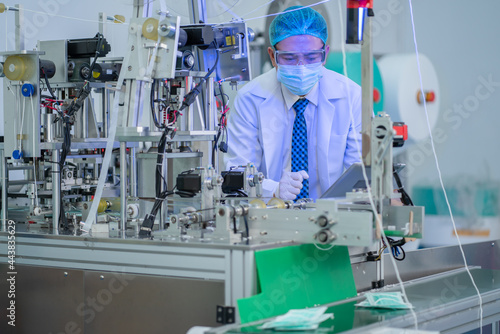 Bilde på lerret Factory worker man with gown uniform check the product during mask producing machine working