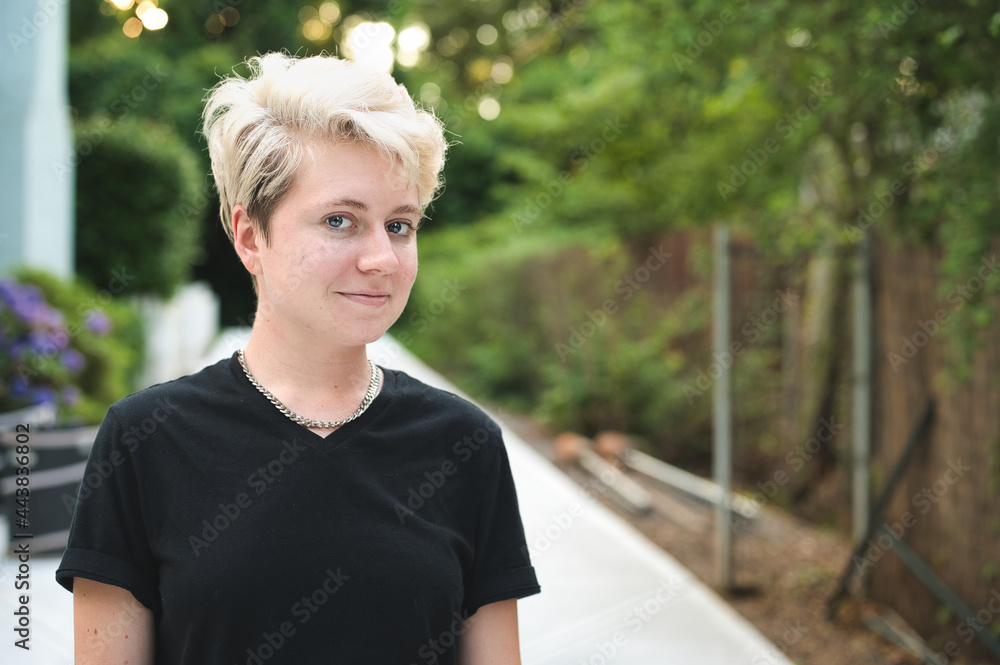 Smiling non-binary person with necklace and black t-shirt Smiling non-binary person with necklace and black t-shirt