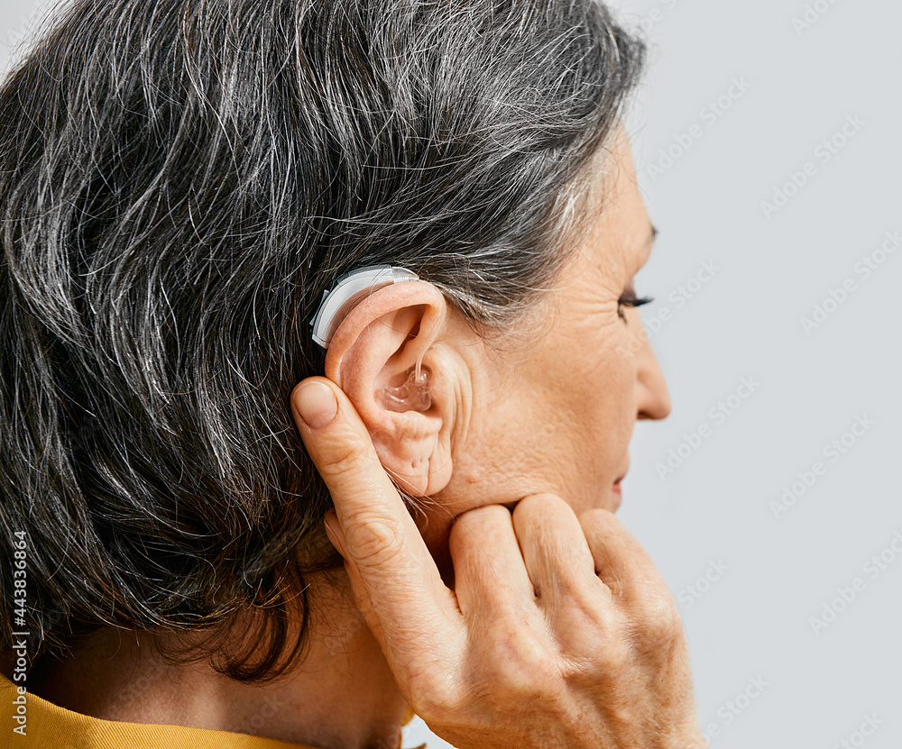 Fototapeta premium Hearing aid behind the ear of senior woman, close-up