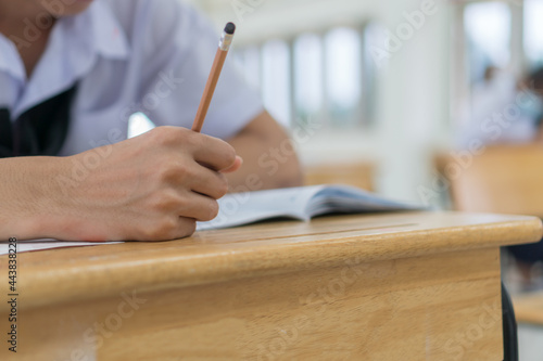 Fototapeta Naklejka Na Ścianę i Meble -  Asian Young Male Student in exam test school of high school or university holding writing document paper answer sheet and lecture final exams in classroom with white uniform of Thailand