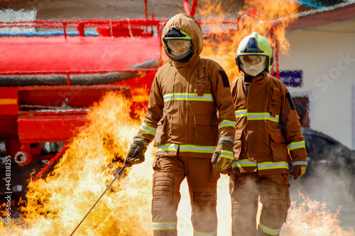 firefighter training., fireman using water and extinguisher to fighting with fire flame in an emergency situation., under danger situation all firemen wearing fire fighter suit for safety.