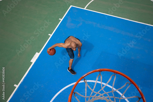 High angle view of young man, male basketball player playing basketball at street public stadium, sport court or palyground outdoors. Summer sport games. photo