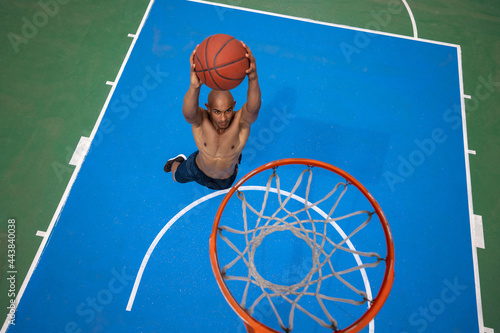 High angle view of young man, male basketball player playing basketball at street public stadium, sport court or palyground outdoors. Summer sport games. © master1305