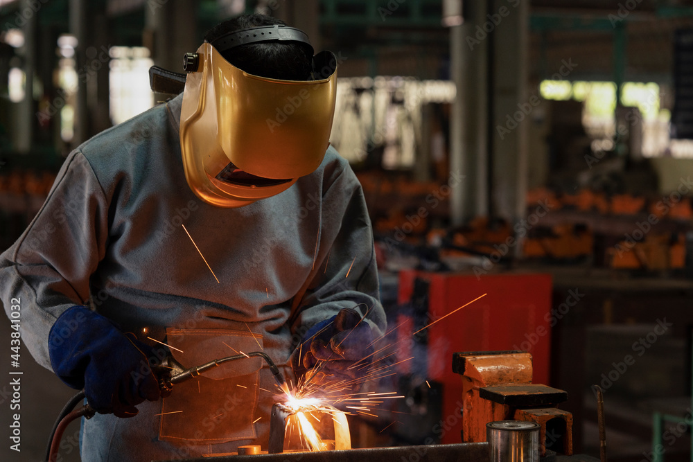 Industrial welder is welding metal part in the construction site.
