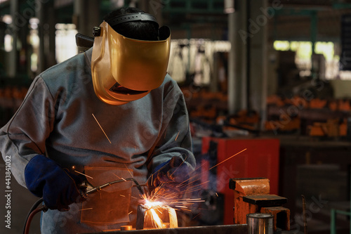 Industrial welder is welding metal part in the construction site.