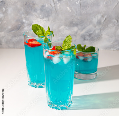 blue juices with strawberries, mint and ice in glasses