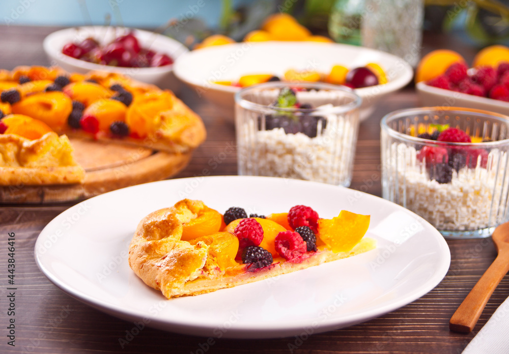 Homemade freshly baked apricot tart with fresh fruits and berries on the white plate.