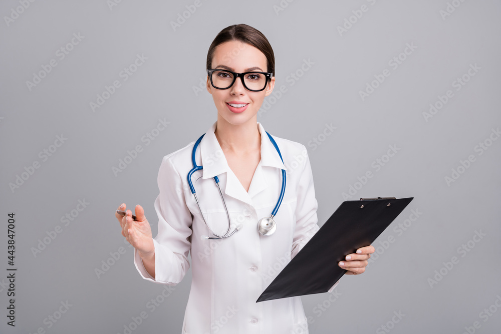 Photo of good mood cute young doc woman dressed white coat writing clipborad smiling isolated grey color background Photo of good mood cute young doc woman dressed white coat writing clipborad smiling isolated grey color background