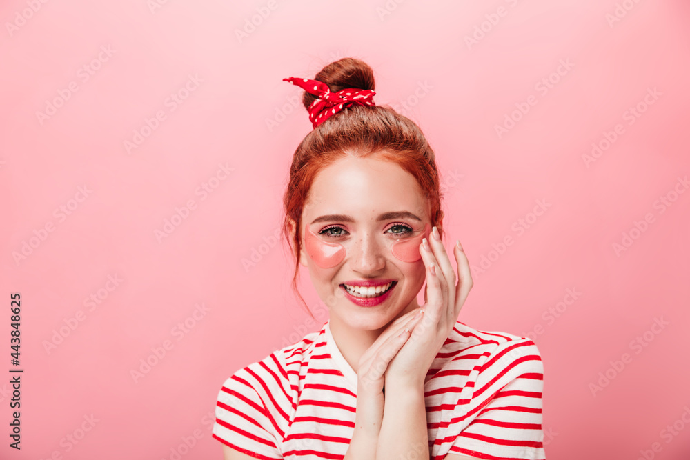 Front view of wonderful girl with eye patches. Studio shot of charming ginger woman doing skincare treatment with sincere smile. Front view of wonderful girl with eye patches. Studio shot of charming ginger woman doing skincare treatment with sincere smile.