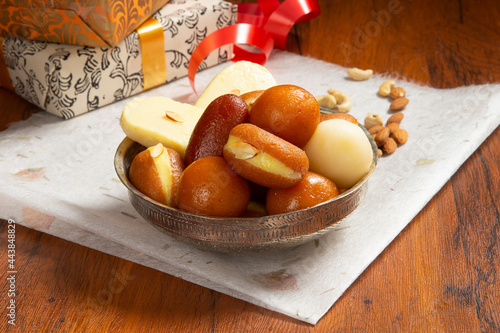 Indian sweets in a plate includes Gulab Jamun, Rasgulla, kaju katli, morichoor / Bundi Laddu, Gujiya or Karanji for diwali celebration photo