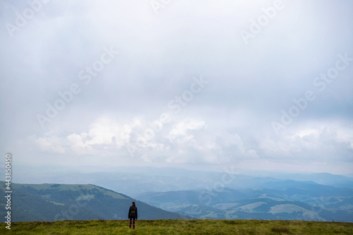 Girl with a backpack in the mountains. Low clouds. Fog. Solitude with nature. Loneliness. Freedom. Tourism.