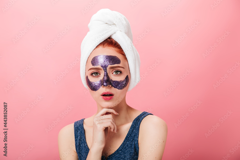 Front view of adorable girl doing spa treatment. Studio shot of wonderful caucasian lady with face mask isolated on pink background. Front view of adorable girl doing spa treatment. Studio shot of wonderful caucasian lady with face mask isolated on pink background.