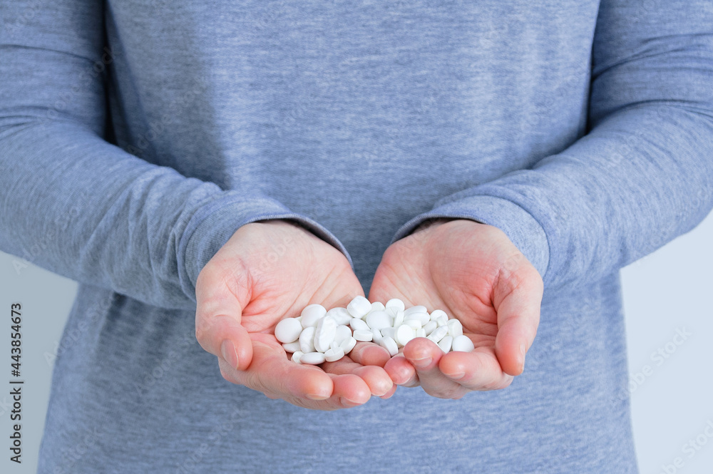 A handful of white pills on palms of a Caucasian woman close-up. A handful of white pills on palms of a Caucasian woman close-up.